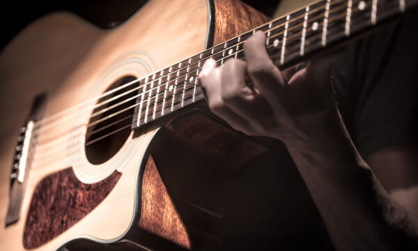 Man playing acoustic guitar on dark background, guitar closeup. A musical concept.